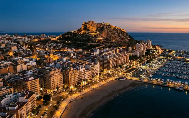 Santa Barbara Castle on rocky Mount Benacantil above Alicante's marina and beachfront at dusk