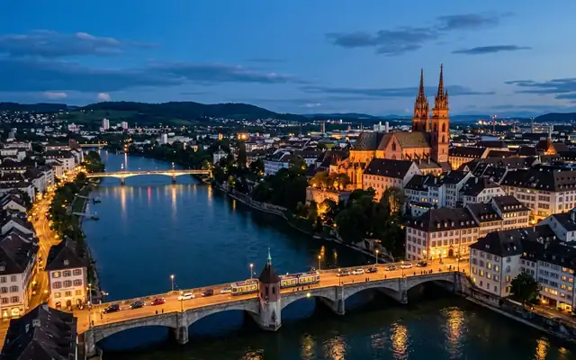 Basel Minster's twin spires above the Rhine and the arched Mittlere Bruecke at dusk