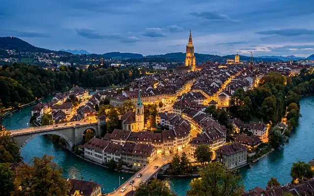 Bern's red-roofed old town in a bend of the turquoise Aare river with the Minster spire at dusk