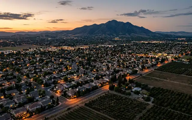 Brentwood at dusk, suburban rooftops beside orchard rows in eastern Contra Costa County with Mount Diablo on the horizon
