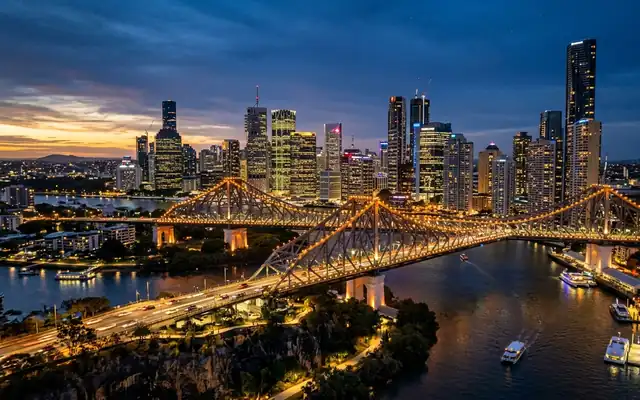 The illuminated Story Bridge over the Brisbane River with the city skyline at dusk