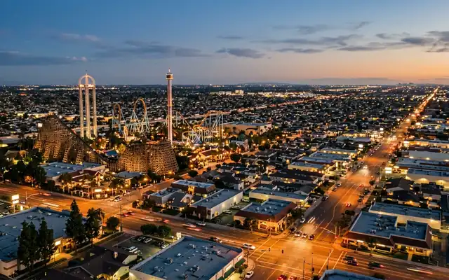 Buena Park at dusk, the wooden coaster and drop towers of Knott's Berry Farm above the flat Orange County grid