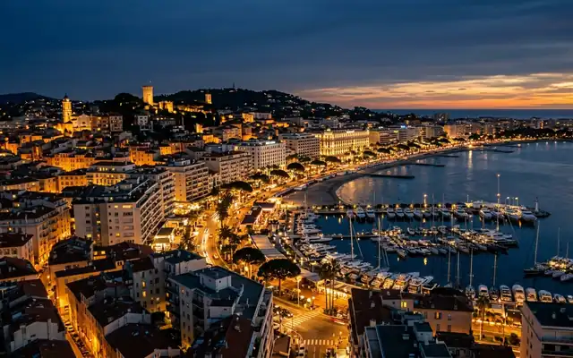 The bay of Cannes with its yacht-filled marina below the old town hill at dusk