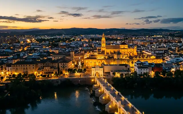 The illuminated Mosque-Cathedral of Córdoba and the Roman bridge over the Guadalquivir at dusk