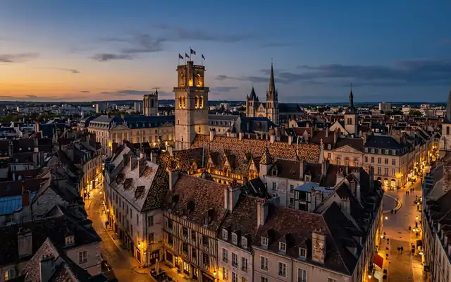 Dijon old town at dusk, the Tour Philippe le Bon above steep roofs patterned with colourful glazed Burgundian tiles