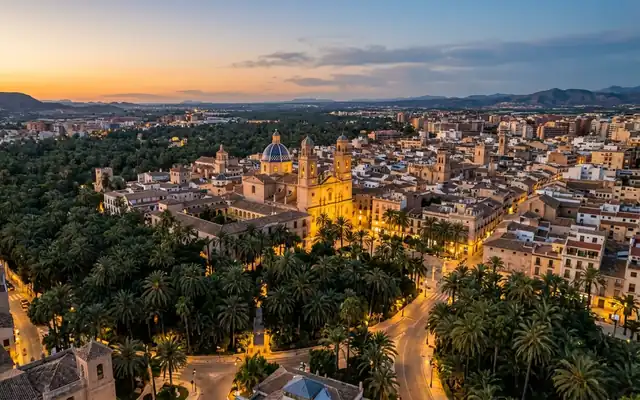 Elche at dusk, the blue tiled dome of the Basilica of Santa Maria rising above the Palmeral palm groves