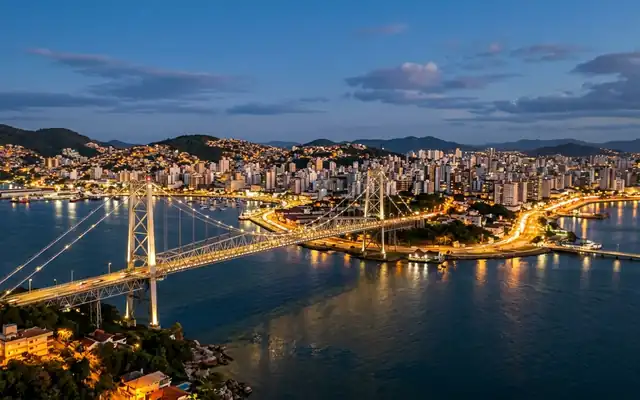 The Hercilio Luz suspension bridge spanning the water to Florianopolis city lights at dusk
