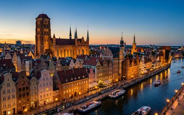 Gdansk at dusk, the brick tower of St Mary's Basilica above gabled merchant houses with the medieval Crane on the Motlawa