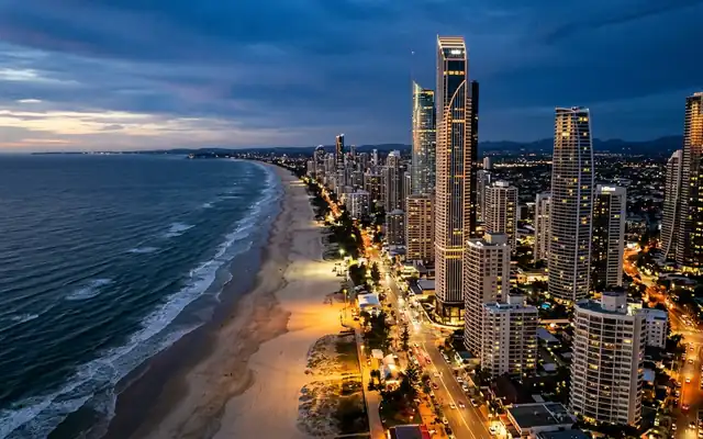 Lit high-rise towers lining the long beach on the Gold Coast at dusk