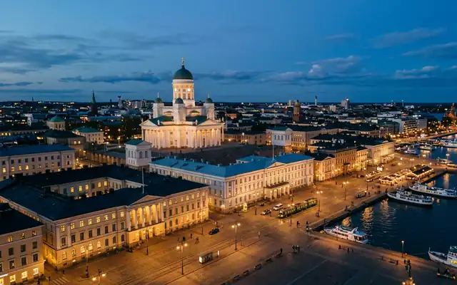 The white Helsinki Cathedral above Senate Square and the lit harbour waterfront at dusk
