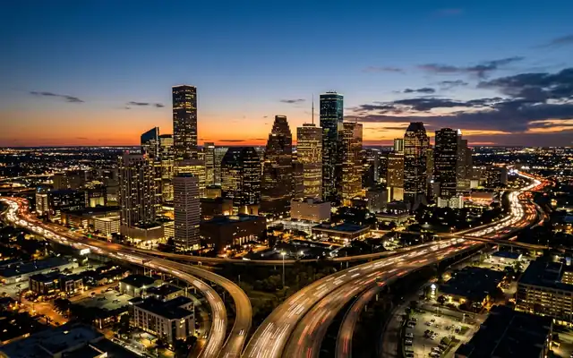 Downtown Houston skyscrapers with curving freeways and light trails at dusk