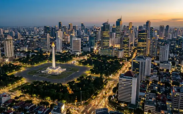 Jakarta at dusk, the gold-flamed Monas obelisk rising from Merdeka Square with the city's high-rise skyline behind