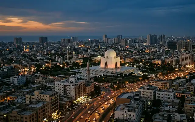 Karachi at dusk, the white marble dome of Mazar-e-Quaid on its raised platform above the sprawling lit cityscape