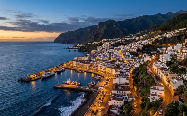 Santa Cruz de La Palma at dusk, balconied waterfront houses and the fishing harbour below steep green volcanic slopes