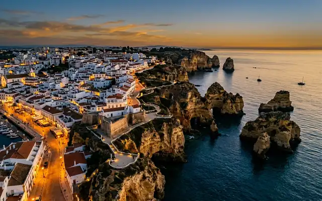 Lagos at sunset, golden sandstone cliffs and sea stacks at Ponta da Piedade beside the whitewashed old town and marina