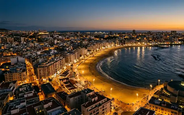 The golden curve of Las Canteras beach and its lit promenade in Las Palmas de Gran Canaria at dusk