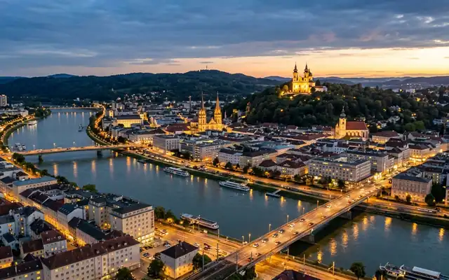 Linz at dusk, the Danube and its bridges below the twin-towered Poestlingberg pilgrimage church on its wooded hill