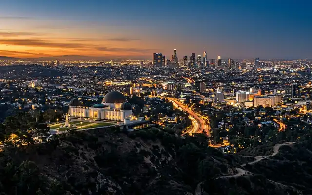 The Griffith Observatory domes above the sprawling downtown Los Angeles skyline at dusk
