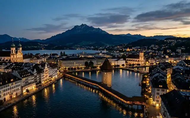 Lucerne at dusk, the wooden Chapel Bridge and its stone Water Tower on the Reuss with Mount Pilatus behind
