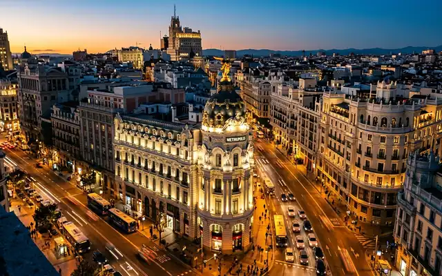 The domed Metropolis Building on Gran Via in Madrid with glowing traffic at dusk