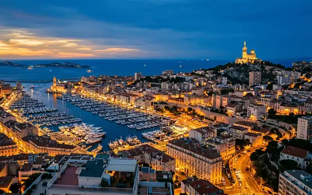 Notre-Dame de la Garde on its hilltop above Marseille's boat-filled Vieux-Port at dusk