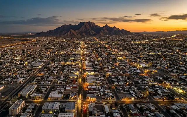 Mexicali at dusk, the flat lit street grid of the border city with Cerro El Centinela on the desert horizon
