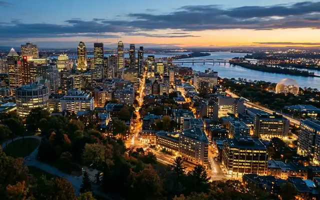 Montreal at dusk from the wooded slopes of Mount Royal, the downtown towers and the St. Lawrence River beyond