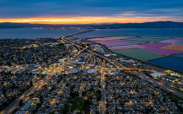 Newark at dusk, the flat East Bay street grid meeting the pink and green salt ponds of San Francisco Bay