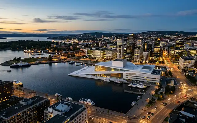 The white sloping roof of the Oslo Opera House on the Oslofjord waterfront at dusk