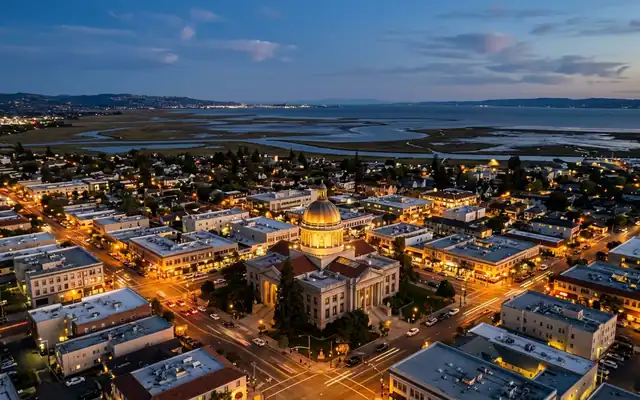 Downtown Redwood City at dusk, the domed historic county courthouse among low blocks with San Francisco Bay marshlands beyond