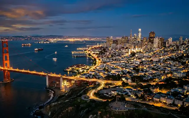 The Golden Gate Bridge leading toward the San Francisco skyline across the bay at dusk