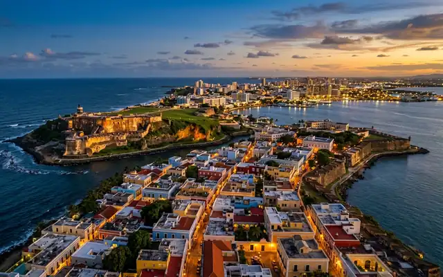 El Morro fortress on its headland with the colorful rooftops of Old San Juan and the sea at dusk