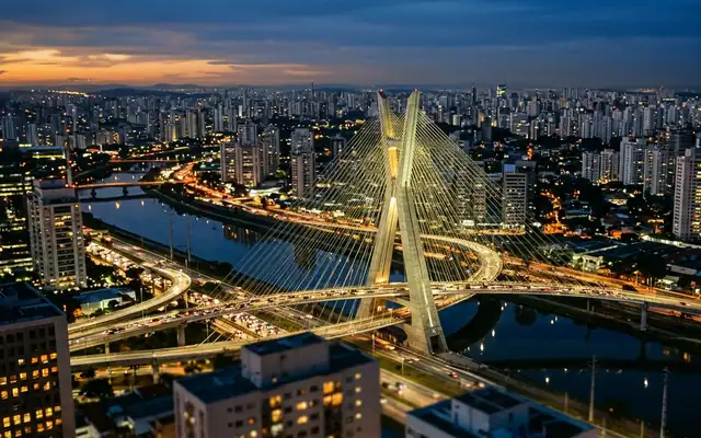 Sao Paulo at dusk, the X-shaped pylon of the Octavio Frias de Oliveira bridge over the river amid endless high-rises