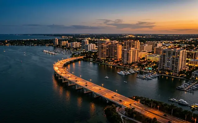 Sarasota at dusk, the John Ringling Causeway bridge curving over the bay toward the bayfront towers and marinas