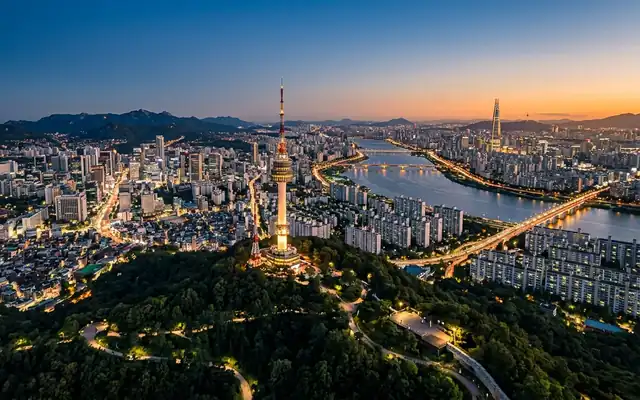 N Seoul Tower on forested Namsan hill above Seoul's sprawling cityscape and the Han River at dusk