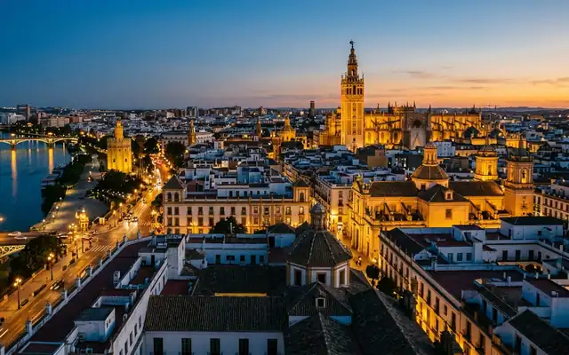The Giralda tower and Seville Cathedral above the old town rooftops of Seville at dusk