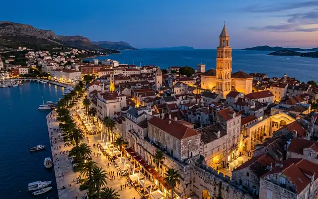 Split old town at dusk, the Saint Domnius bell tower above the Diocletian's Palace rooftops and the palm-lined Riva waterfront