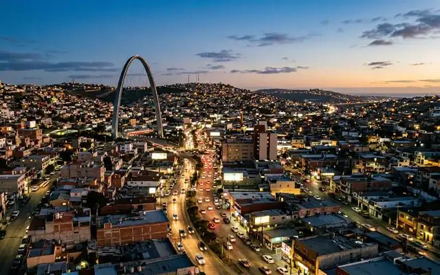 The Millennial Arch rising over a busy avenue in Tijuana at dusk