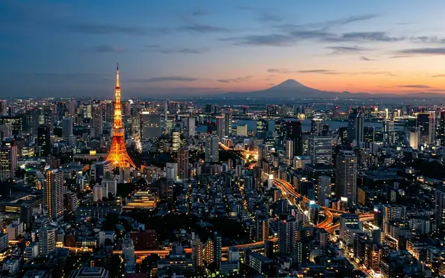 Tokyo Tower glowing above the city sprawl with Mount Fuji on the horizon at dusk