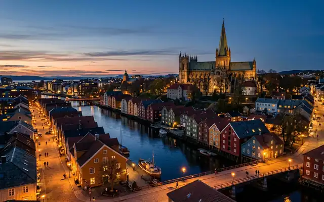 Trondheim at dusk, Nidaros Cathedral above the colourful wooden wharf houses lining the Nidelva river and its footbridge