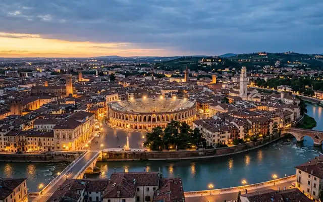 The Roman Arena amid Verona's terracotta rooftops by the Adige river at dusk