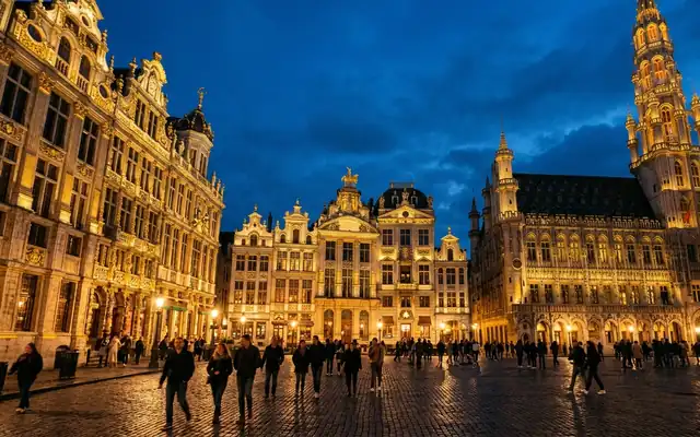The Grand-Place in Brussels, Belgium at dusk, gilded guildhall facades and the Gothic town hall spire lit above the cobbled square