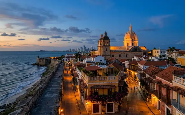The walled old city of Cartagena, Colombia at dusk, the lit dome of San Pedro Claver above colonial balconies and tiled roofs