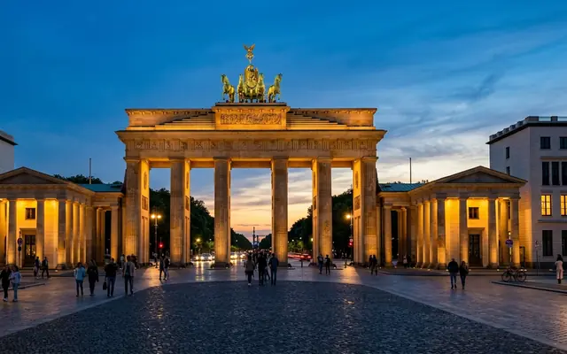 The Brandenburg Gate in Berlin, Germany at dusk, floodlit sandstone columns beneath the gilded Quadriga chariot and its four horses