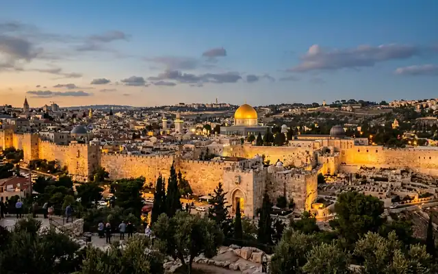 The Old City of Jerusalem, Israel at dusk, the golden Dome of the Rock rising above lit limestone walls