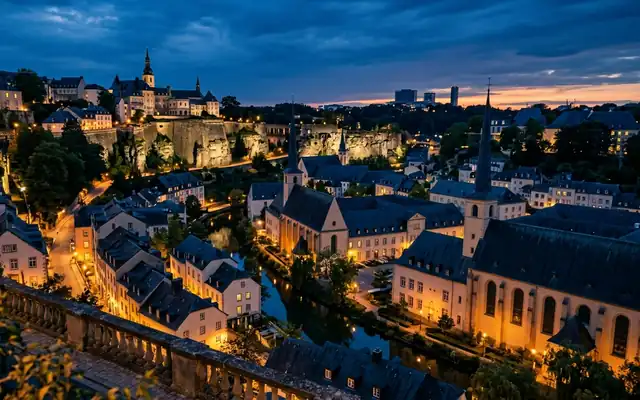 Luxembourg City at dusk from the Chemin de la Corniche, the Bock cliffs and fortifications above the lit Grund quarter