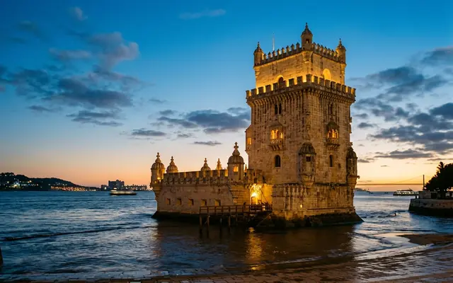 Belem Tower in Lisbon at dusk, the Manueline stone tower and its bastion standing at the edge of the Tagus River