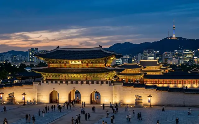 Gwanghwamun gate and the tiled roofs of Gyeongbokgung Palace in Seoul at dusk, with N Seoul Tower on the hill behind