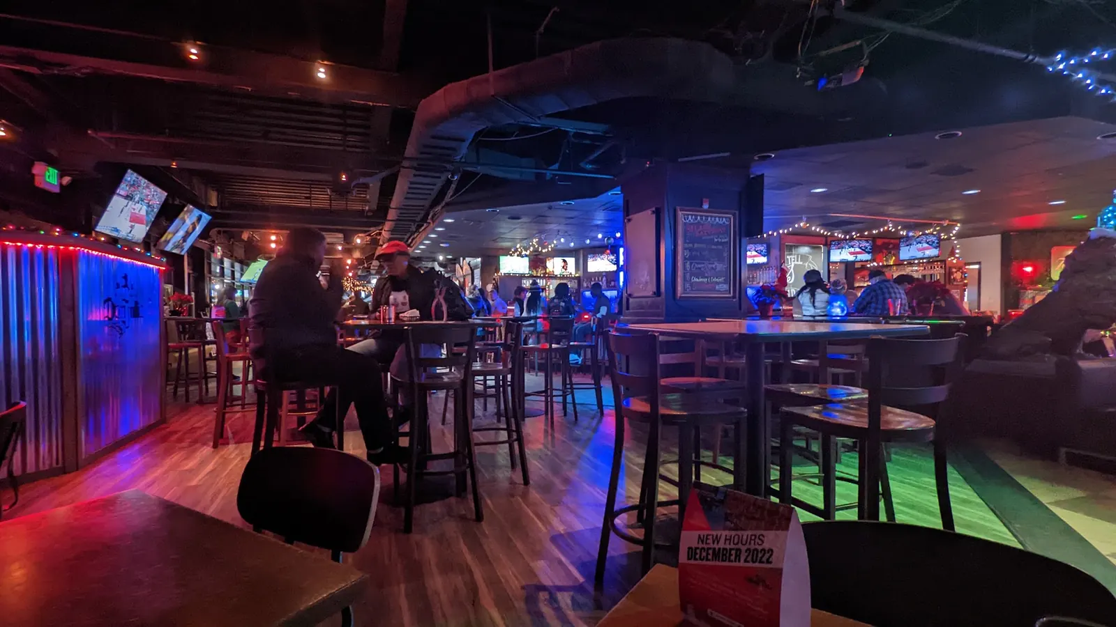 Bar tables and stools under red and blue club lighting inside Nottingham’s Tavern in Columbia