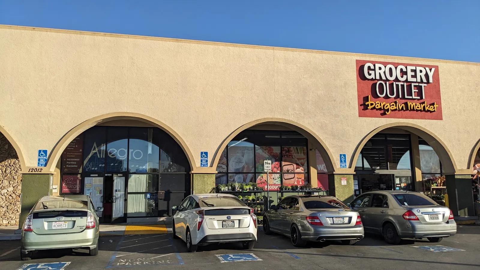 Storefront entrance with Allegro window signage beside a neighbouring grocery store